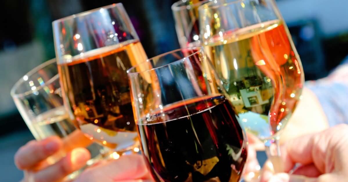 Weingläser beim Anstoßen mit Weißwein und Rotwein